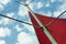 Red sail on a metal mast against a blue cloudy sky