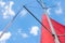 Red sail on a metal mast against a blue cloudy sky