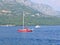 Red sailing boat, white boat, hills in the background