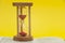 Red sand hourglass on top of open Holy Bible in the Book of the Prophet Ezekiel chapter 7 verse 7. Isolated on yellow background