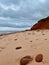 Red sandstone cliffs and the sand at Cavendish Beach under cloudy sky, Prince Edward Island, Canada