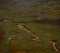 Red sandstone mineral sediment coloured river stream in green grass valley at Vinicunca Rainbow Mountain in Cusco Peru