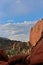 Red Sandstone pinnacles rising up among pine trees backed by cumulus clouds and a blue sky at Garden of the Gods in Colorado