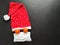 Red santa claus hat, tangerines instead of eyes and medical mask on black background