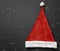 Red santa claus hat with white bubo and edging on a dark background with white flying snow grains