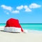 Red santa hat on white tropical beach sand - Christmas or New Ye