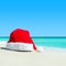 Red santa hat on white tropical beach sand - Christmas or New Ye