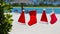 Red Santa hats and Christmas stocking hanging on tropical beach