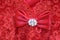 Red satin bow with jeweled center on red lace dress - closeup selective focus very red and pretty