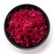 Red sauerkraut in a black ceramic bowl isolated on white. Top view