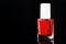 Red scarlet nail polish in bottle isolated glossy black background, copy space, selective focus