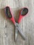 Red scissors closed on a wooden table.