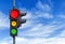 Red semaphore light with yellow and green and cloudy sky