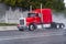 Red semi truck rig with long cab on raining highway