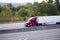 Red semi truck trailer reefer on green highway