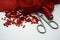 Red sequins, spool of red thread,needle and scissors on rippled red silk background.