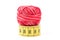 Red sewing thread on top of yellow measuring tape. Sewing accessories and tools.