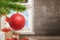 Red shiny Christmas ball on tree. Gifts, decorations, wall and window in background with copy space