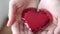 Red shiny decorative shining heart in the hands of a woman.