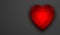 Red shiny reflective glass heart on grey background