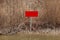 Red sign in the bare bushes on the lake shore