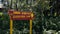 Red sign next to green vegetation giving easy direction with yellow letters and arrow towards ranamese lake.