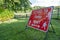 A red sign warning about the Coronavirus pandemic and social distancing in a field at an outdoor event