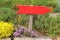 Red signpost in a garden between flowers