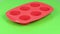 Red silicone form for cooking muffin and cupcake on green background.  Side view. Loop motion. Rotation 360.