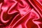 Red silk background, satin fabric background. Pleated fabric.