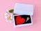 Red silk Valentine heart and a key on black velvet into a white jewelry gift box on a pastel pink background. Key to my heart