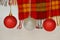 Red and silver Christmas balls against a woolen red and yellow checkered scarf with a fringe. Concept of holidays, Christmas and N