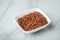 Red skinned raw Jasmine rice in porcelain bowl on marble background