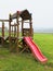 Red slide from wooden crawl construction on modern kids playground