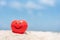 Red smile heart shape on pile of sand with blue sky background.