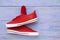 Red sneakers hang on laces. On violet wooden background