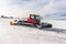 Red snow-grooming machine on snow