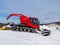 A red snowcat at a ski resort is preparing to tamp the snow