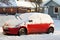 A red snowed car stands in the parking lot