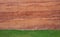 Red soil wall background and green grass field