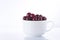 Red sour cherries in a white cup on a white background, isolated, close up