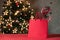 Red sparkling shopping bag mockup with copy space, pine tree branch decoration and candy cane inside, on red table