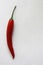 Red spicy pepper lies on a white textural background  at the left side