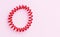 Red spiral rubber bands for hair on a pink background close-up, copy space for text