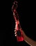 Red Splashing of bottle drink. Refreshing vitamin beverage splash from plastic container on black background. Male hand