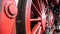 Red spoke wheels with rods and pistons of old train locomotive a