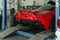 Red sports car raised on a lift in a car repair shop, rear bumper