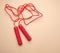 red sports rope for jumping and cardio load on a beige background