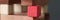 Red square wooden cube standing among wooden blocks closeup