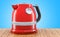 Red stainless electric tea kettle, retro design on the wooden ta